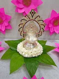 there is a small silver statue on top of some white flowers and green leaves in front of it