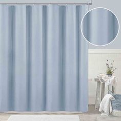 a blue shower curtain next to a white rug in a bathroom with a round mirror on the wall