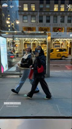 two women walking down the street in front of a building