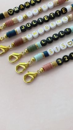 four different colored beads with gold scissors on them that spell out the names of people