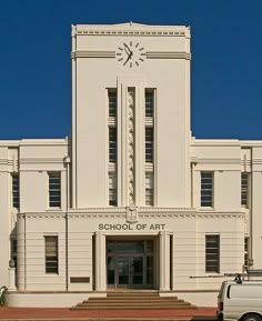 a large white building with a clock on it's face and stairs leading up to the entrance