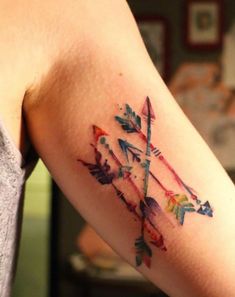 a woman's arm with an arrow tattoo on it