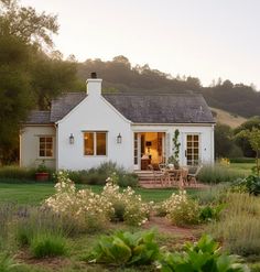 a small white house sitting on top of a lush green field