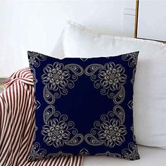 a blue pillow sitting on top of a white couch next to pillows and a striped blanket