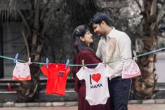 a man and woman standing next to each other holding shirts on a clothes line,