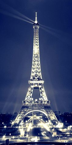 the eiffel tower lit up at night in black and white with street lights