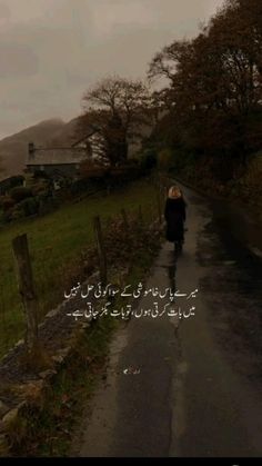 a woman walking down the road in front of a fence with an arabic quote on it