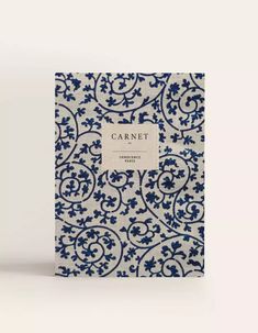 a blue and white book with an ornate design on the cover, sitting in front of a