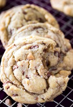 chocolate chip cookies stacked on top of each other in front of a wire cooling rack