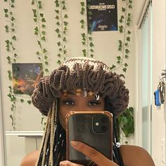 a woman with dreadlocks taking a selfie in front of a mirror holding her cell phone