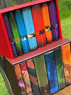 a stack of colorful books sitting on top of a wooden table next to a green field