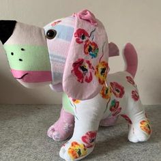 a stuffed dog with flowers on it's head and tail is standing next to a wall