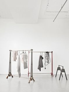 an empty room with clothing racks and clothes hanging on the rails in front of it