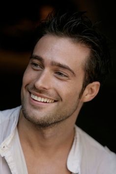 a man smiling and wearing a white shirt