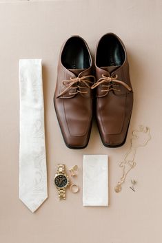 a tie, dress shoes, and watch are laid out on the floor