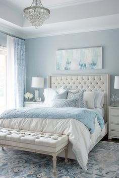 a bedroom with blue walls, white furniture and a chandelier hanging from the ceiling