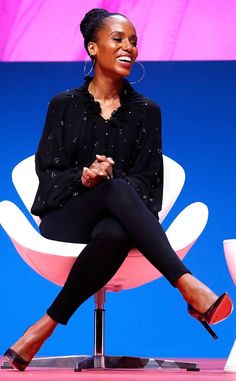 a woman sitting on top of a white chair in front of a blue wall and purple background