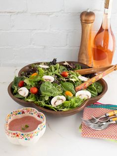 a salad in a bowl with dressing next to it