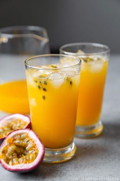 two glasses filled with orange juice and some fruit