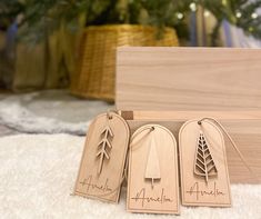 three wooden tags with trees on them sitting next to a christmas tree in a box