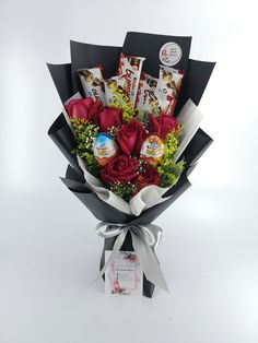 a bouquet of red roses and chocolates wrapped in black paper