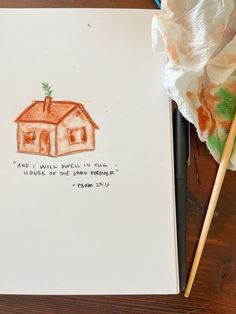 an open notebook with a drawing of a house on it and a pencil next to it