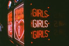 neon signs on the side of a building that says girls, girls, and hearts