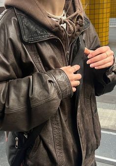 a woman in a leather jacket is standing on the street