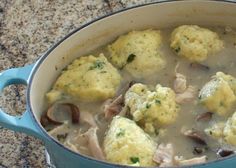 a pot filled with meat and dumplings covered in gravy on top of a counter