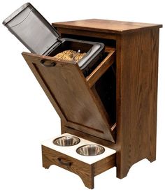 an open wooden cabinet with two bowls and a dog food dish in the bottom drawer