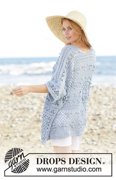 a woman standing on top of a beach next to the ocean wearing a straw hat