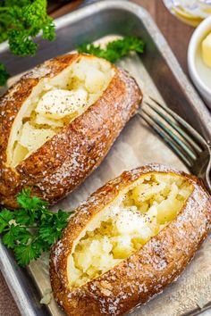 two pieces of bread with butter and parsley on top sitting in a baking pan