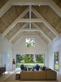 a living room filled with furniture and a large window covered in wood planks on the ceiling