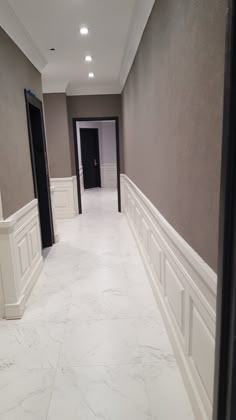 an empty hallway with marble floors and white trim