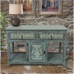 a blue table with two drawers and a lamp on it in front of a stone wall