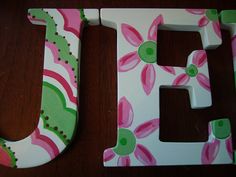 the letters are painted pink and green with flowers on them, along with a polka dot design