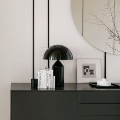 a black dresser with a mirror and vase on it in front of a white wall