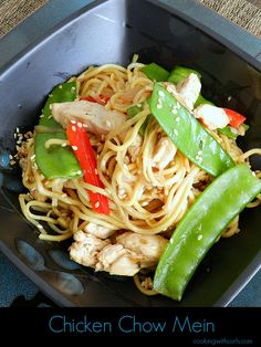 chicken chow mein in a black bowl with green peppers and snap peas on the side