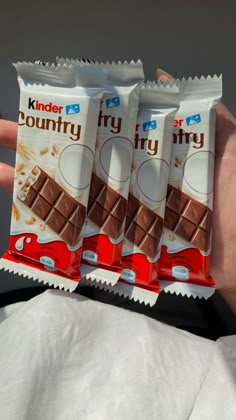 three packets of kinder's country chocolate are held in the palm of someones hand