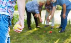 three people are playing with balls in the grass and one person is reaching for it