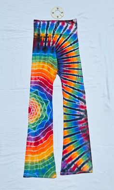 a tie - dyed pair of colorful pants hanging on a clothes hanger in front of a white background