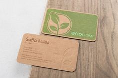 two business cards sitting on top of a wooden table next to each other with the word eco