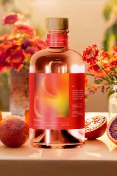 a bottle of blood orange juice sitting on top of a table next to flowers and fruit