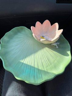 a lotus flower sitting on top of a green leafy bowl in the back seat of a car