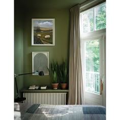 a bed room with a neatly made bed next to a window and a painting on the wall