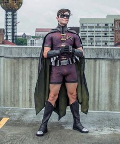 a man dressed as batman standing on top of a cement wall with his hands in his pockets