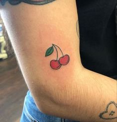 a person with a tattoo on their arm has cherries tattooed on her left arm