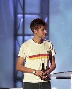 a young man holding a beer standing next to a podium