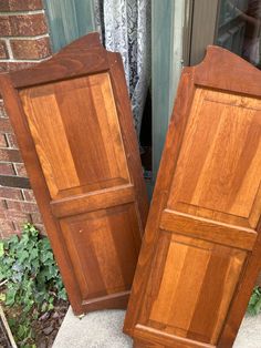 two wooden doors sitting next to each other on the ground in front of a brick building