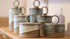 four canisters with rings on them sitting on a shelf next to each other